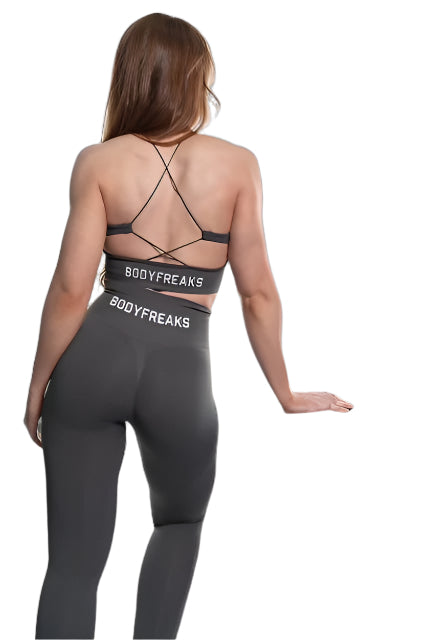 Woman in a Bodyfreaks workout outfit stands next to a black box labeled "BODYFREAKS," facing away